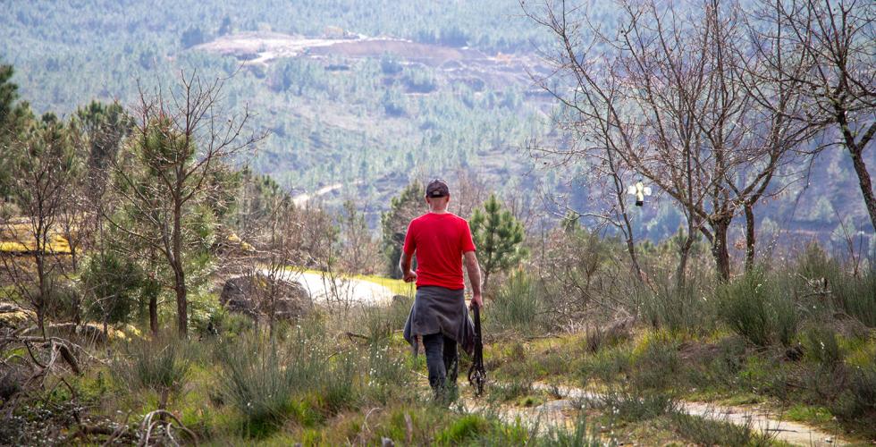 En mann går i fjellet. Et dagbrudd kan ses i fjellet i bakgrunnen.