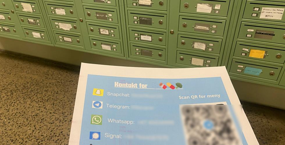 Lapp med kontaktinformasjon til en person som selger rusmidler. Grønne postkasser i bakgrunnen.