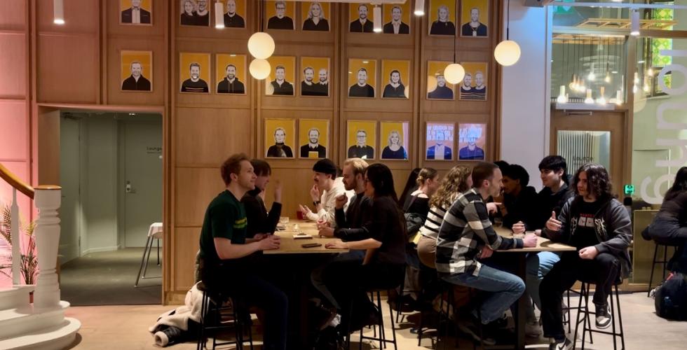 Mennesker sitter rundt langbord og snakker
