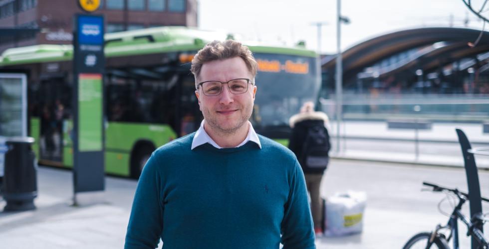 Adrian Pracon står foran en buss