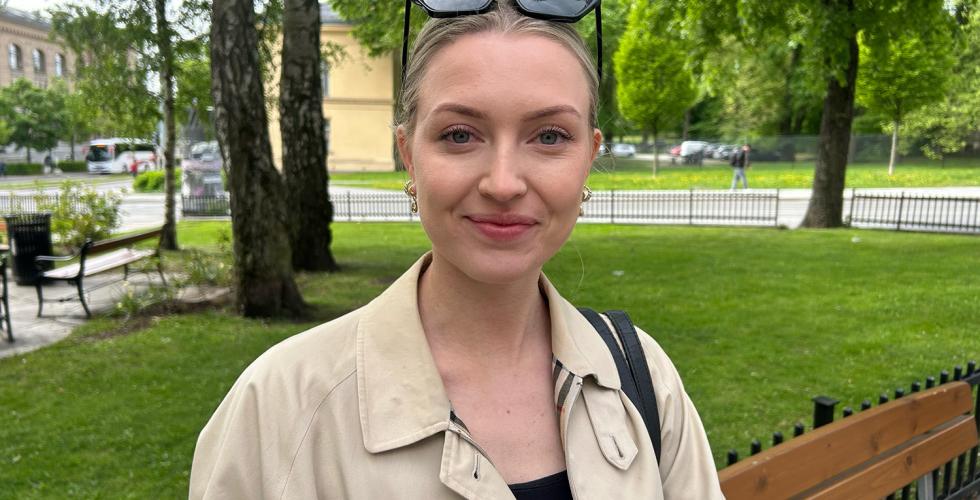 Ung dame som smiler til kamera mens hun venter på bussen.