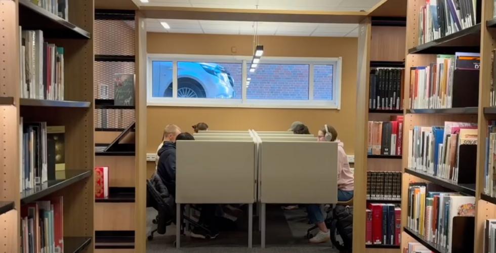 Et bibliotek med båser og studenter som leser