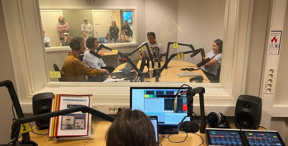Programleder styrer livesending på radio og ser inn på studio. 