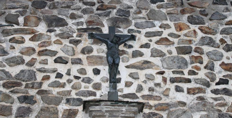 På en steinvegg, henger et kors med Jesus på