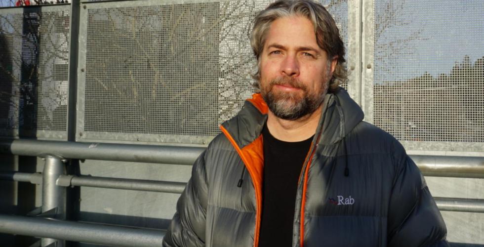 Mann står i direkte sollys med et alvorlig ansiktsuttrykk.