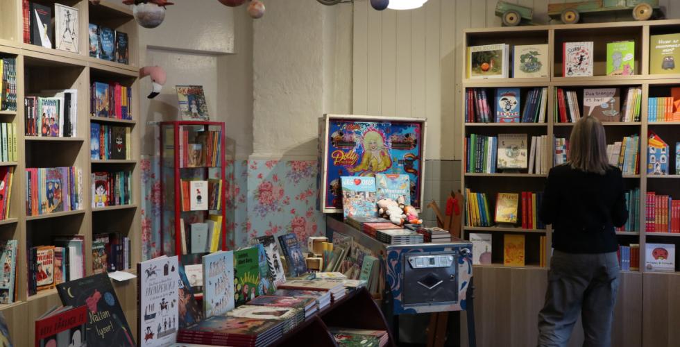 Dame står i en bokhandel og ser på barnebøker.