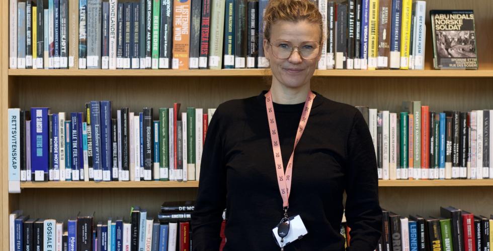 Frid Hamsun står foran en bokhylle. Hun er seksjonsleder på Deichman Lambertseter