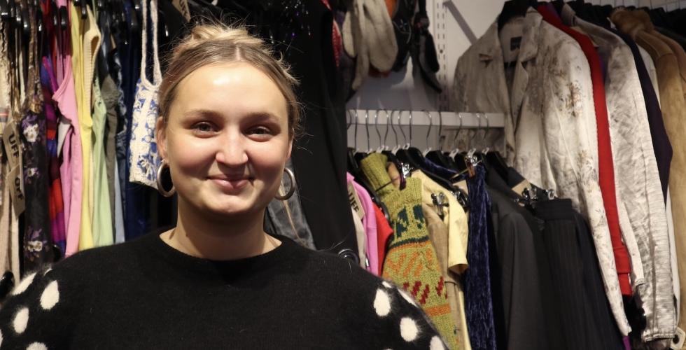 Sunniva som står i bruktbutikken UFF, der hun jobber.