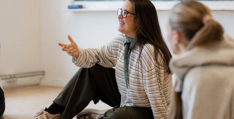 Martine Tufvesson  Lundberg sitter p&aring; gulvet i et klasserom sammen med elever