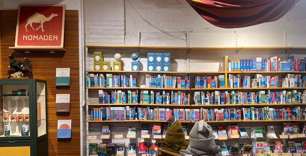 Innsiden av butikken Nomaden. Bokhyller, utstilling med turkl&aelig;r og butikkens skilt. 