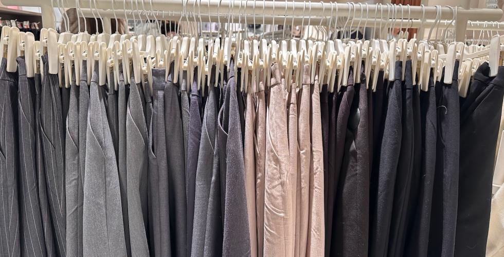 Hengende bukser p&aring; stativ inne p&aring; klesbutikk