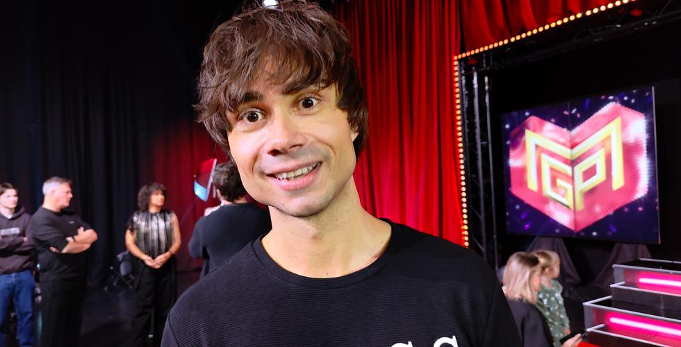 R&oslash;d gardin. Mann foran. Smiler. Sort genser.