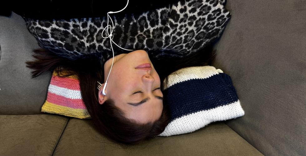 Jente sover med musikk i &oslash;rene.