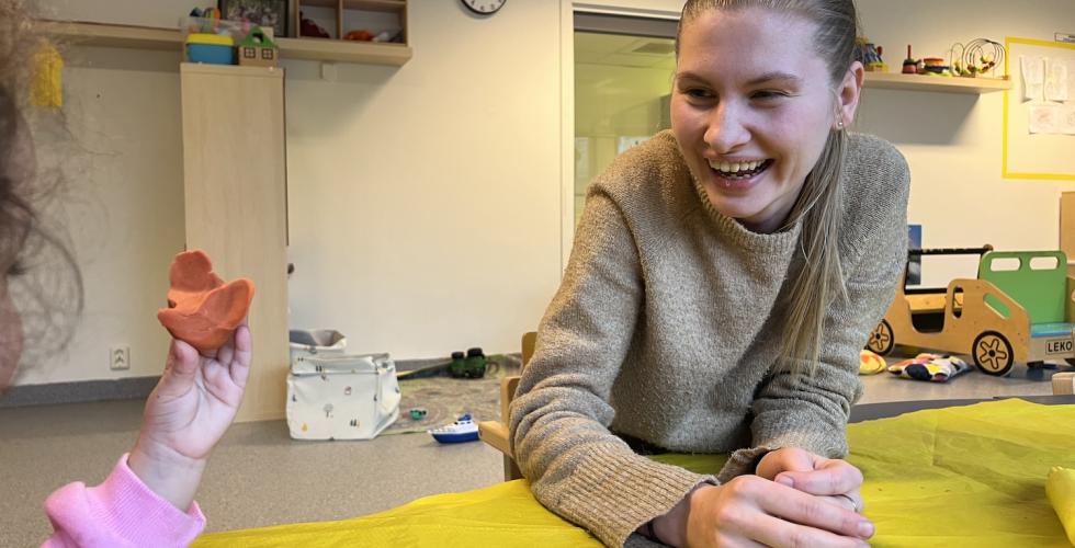 Karoline Utvik sitter &aring; leker med plastelina med barna i barnehagen.