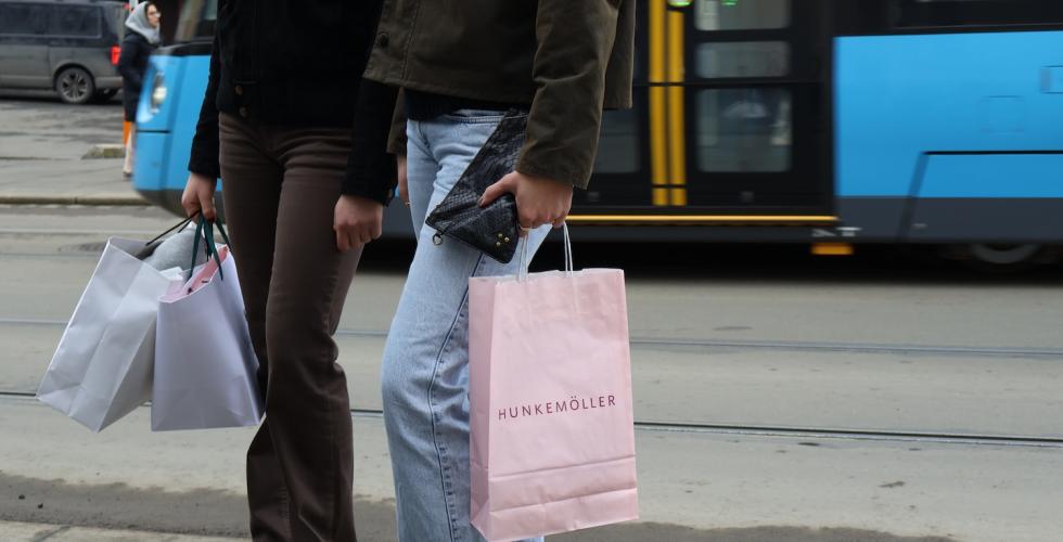 handleposer blir holdt av to jenter bildet er tatt fra livet og ned. ser trikken i bakgrunn