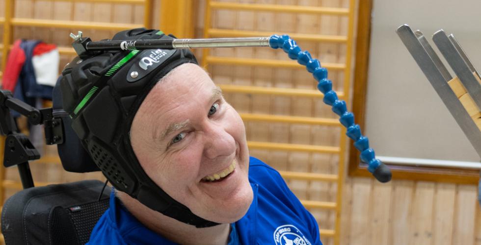 Christer smiler til kameraet med en hjelm med en antenne p&aring; hodet