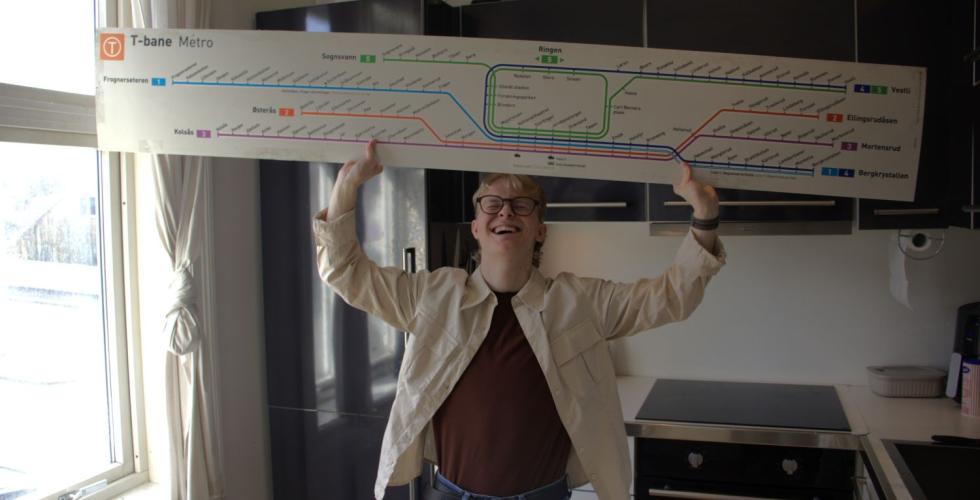Mann holder opp skilt med alle t-banelinjene