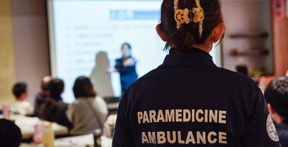 En ambulansemedarbeider st&aring;r i et klasserom.
