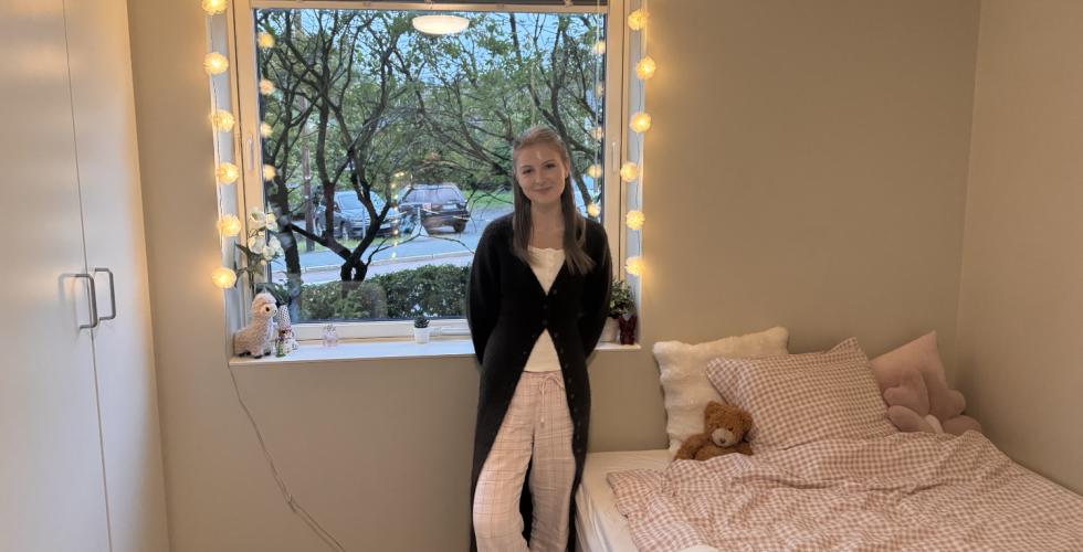 Studenten Caroline som st&aring;r i studentboligen sin.