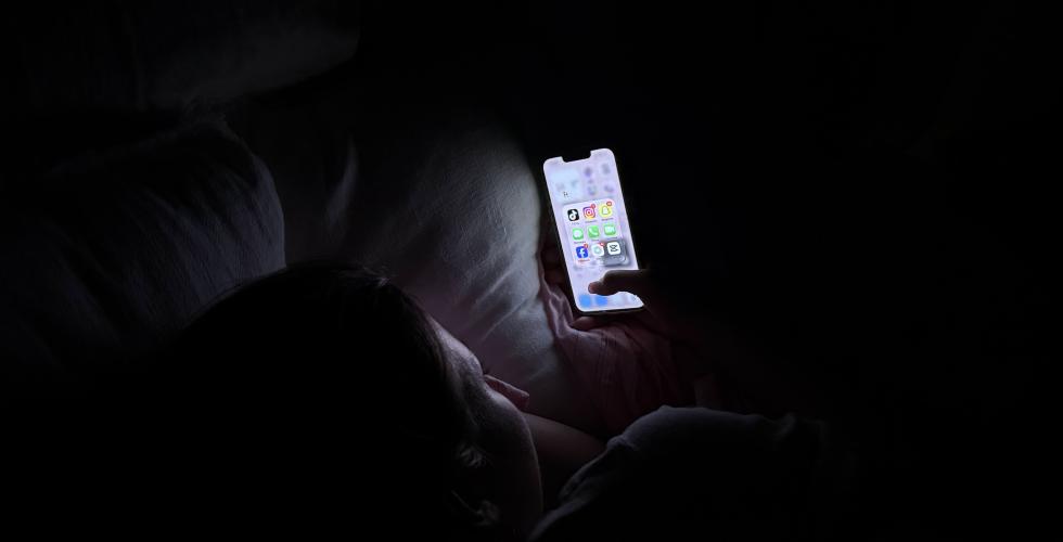Jente ser p&aring; mobiltelefonen fylt med sosiale medier.