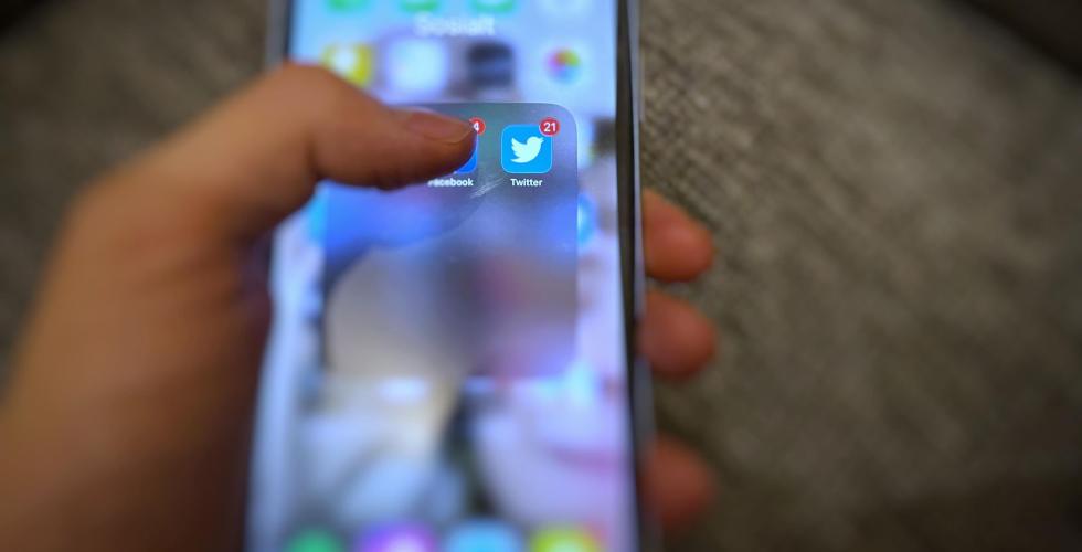 En hånd som holder en telefon med bilde av Twitter applikasjonen 