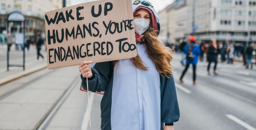 Demonstrant med et skilt hvor det står at mennesker også er utrydningstruet. 