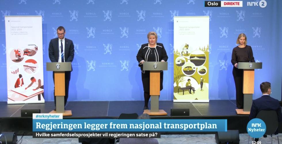 Erna Solberg, Guri Melbye, og Knut Arild Hareide står ved siden av hverandre på et podium, og legger frem den nasjonale transportplanen for 2022-2033.