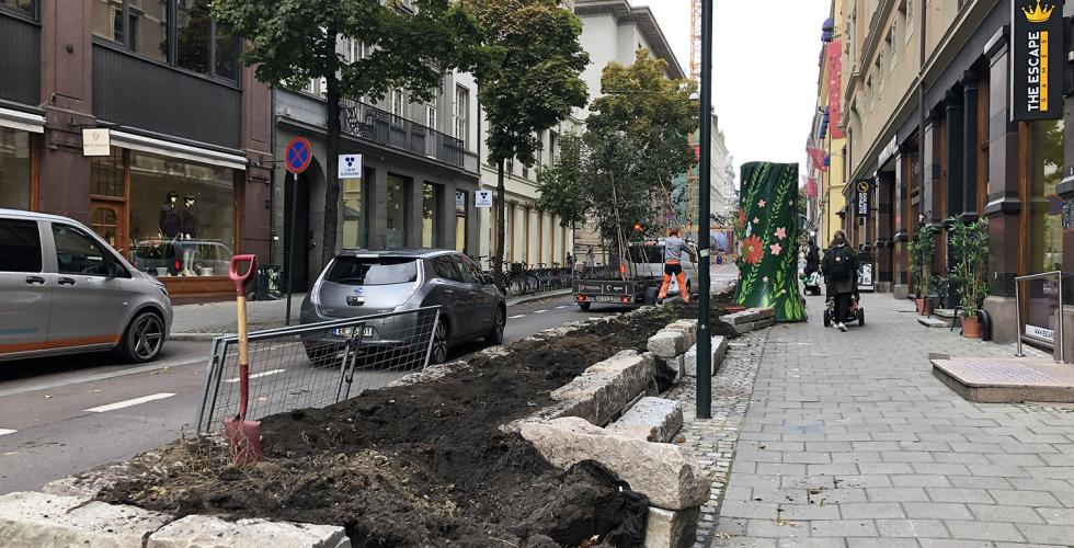 Trær bæres på en tilhenger ved siden av det tomme blomsterbedet