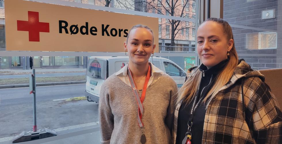 Seniorkonsulenter i Barnas Røde Kors, Martine Jakobsen og Marielle Halvorsen, avbildet i Røde Kors' lokaler i Hausmannsgate 23, foran et Røde Kors-skilt.