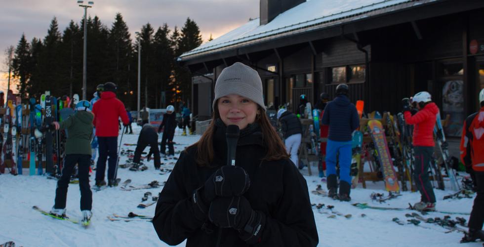 Reporter står i vinterparken i Oslo. Hun er omringet av skikjørere.