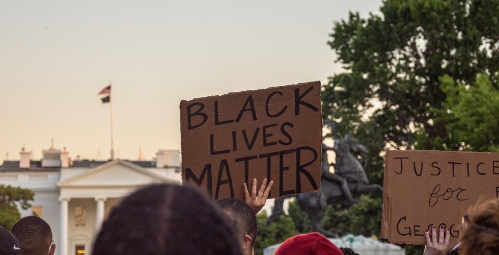 Folk i protest som holder plakater med teksten "Black Lives Matter"