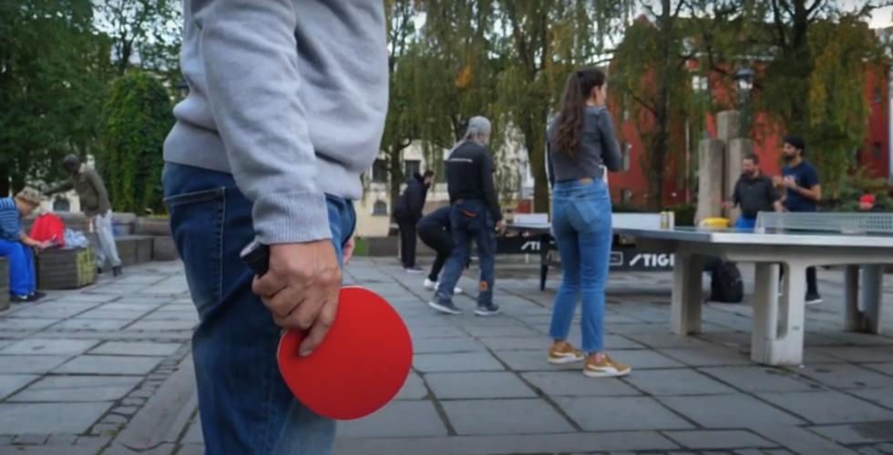 Mann med olabukse, som holder rød bordtennisracket.