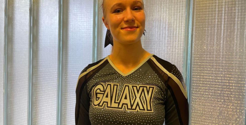 Smilende blond jente i svart cheerleaderdrakt