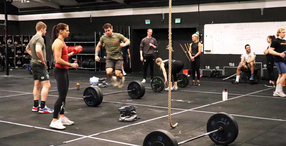 Utøvere som trener Crossfit. En hopper over vektstanga. 