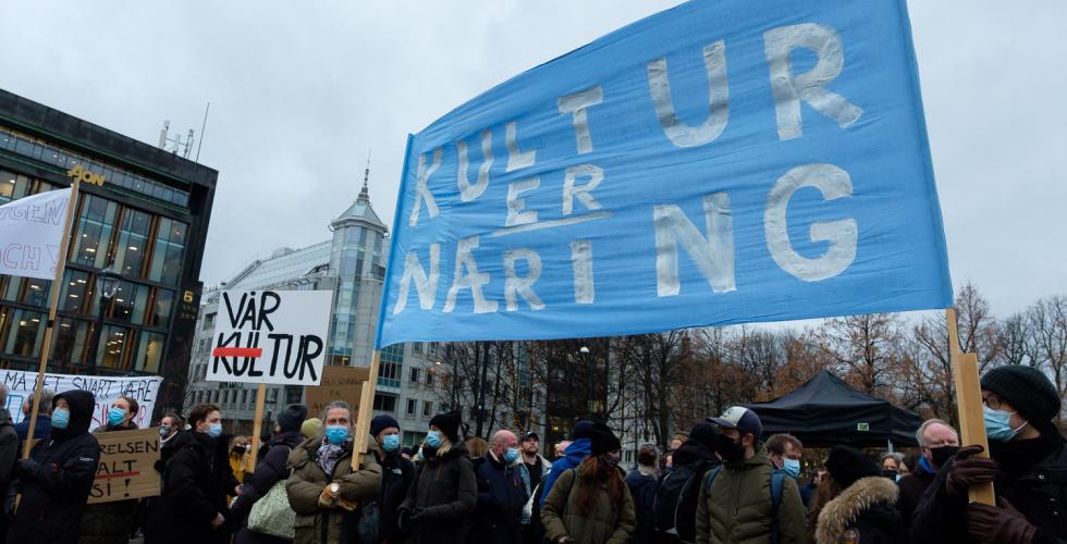 Demonstranter fra kulturlivet holder plakater og bannere foran Stortinget.