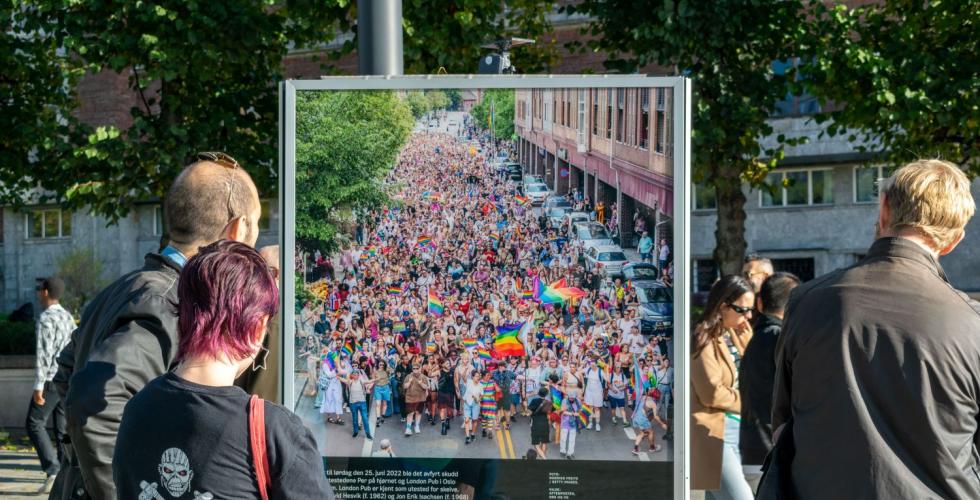 Folk står og ser på et bilde av pride parade