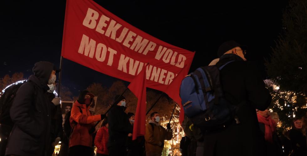 Demonstranter som holder plakat med teksten: "Bekjemp vold mot kvinner!"