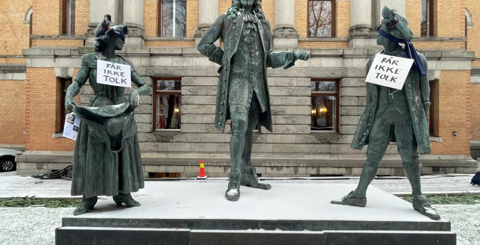 Plakater med teksten  "får ikke tolk" på Ludvig Holdberg statue 