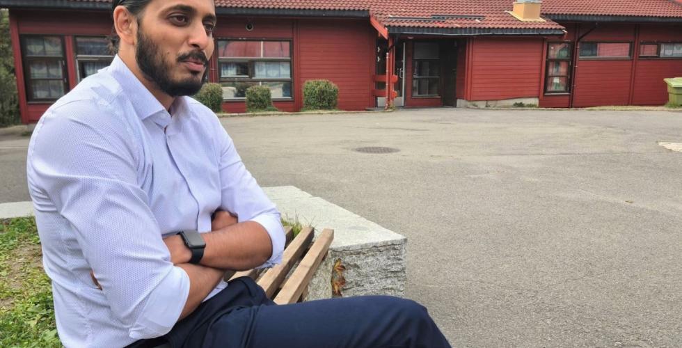 Ap-politiker Farukh Qureshi sitter på en benk utenfor Bjørndal skole.