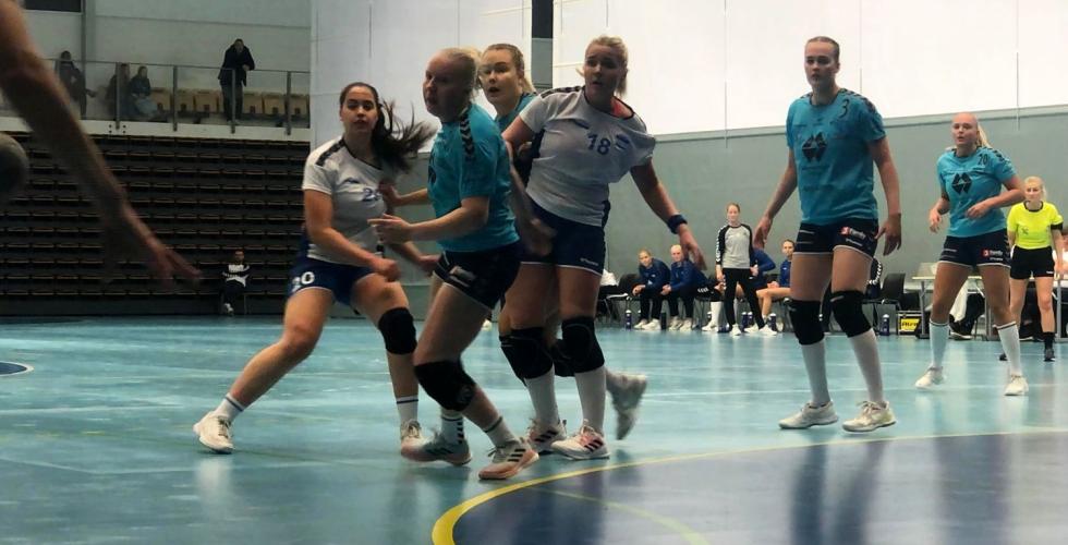 Håndballspillere i kamp med blå bakgrunn