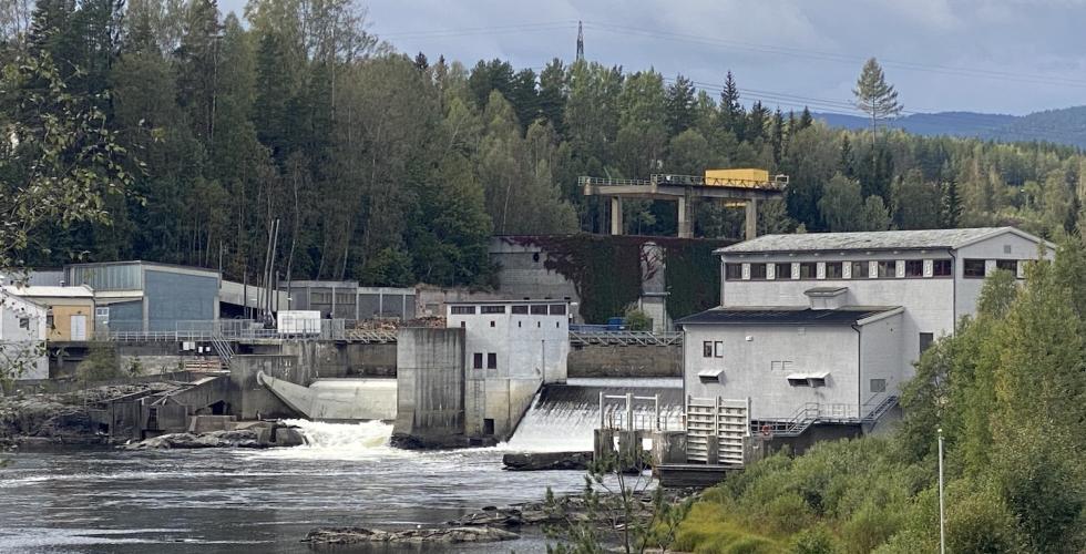 Avstandsbilde av Hellefoss elvekraftverk som viser vannfallet fra kraftstasjonen