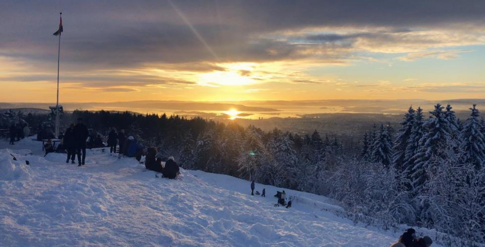 solnedgang på toppen av Grefsenkollen i Oslo. Mennesker og snø, flagstang