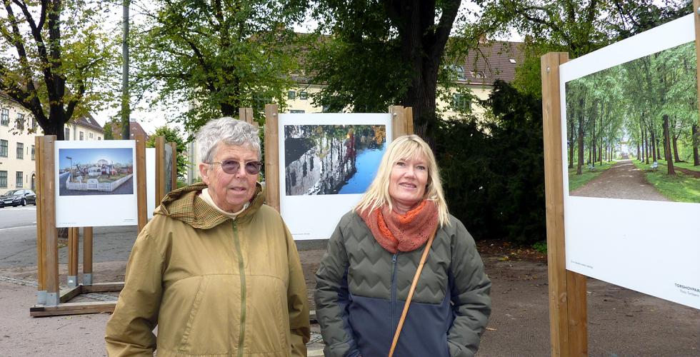 Bilde av to kvinner foran en fotoutstilling ute i en park 