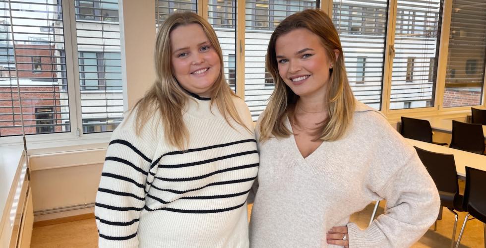 Ingerid Bernhoft (25) og Anea Sorthe (23) smiler til kameraet i et av OsloMet sine klasserom. 