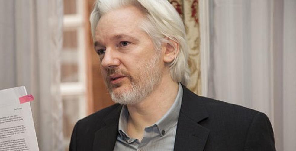 Den australske varsleren og journalisten Julian Assange holder opp et dokument. 