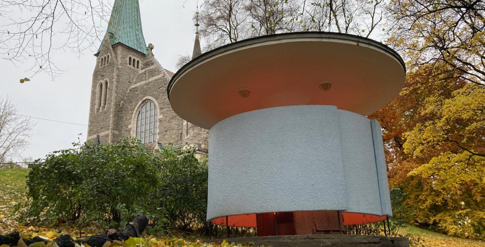 Kjærlighetskarusellen står nedenfor en kirke i Stensparken, til høyre i bildet. Det lyser fra bygget.  