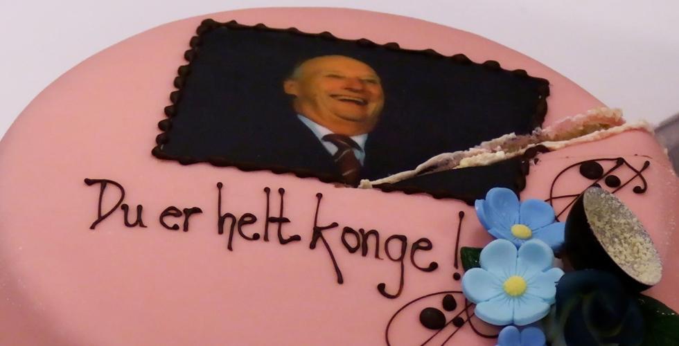 En rosa kake med bilde av kong Harald på. Teksten under står det "Du er helt konge"