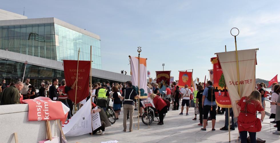 Samling av fagorganiserte med faner og protestplakater i Fagforbundet Teater og Scene, Norsk tjenestemannslag og CREO utenfor Operaen i Oslo. Rett før demonstrasjonstoget Kulturmarsen.