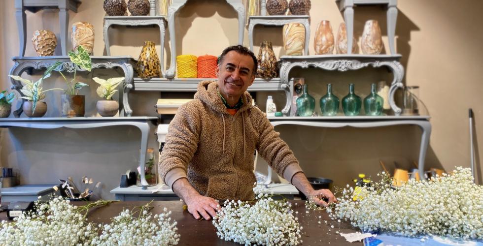 Mahmut Aydın star bak kassen i butikken Blomsterista og binder buketter.