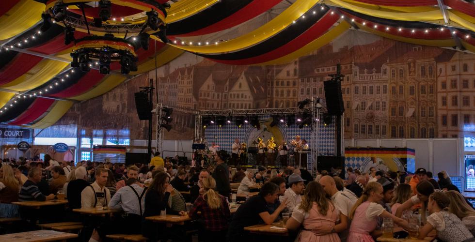 Inn i teltet til oktoberfest. Vi ser flere personer som har det gøy og hører på de tyske sangene i bakgrunnen.